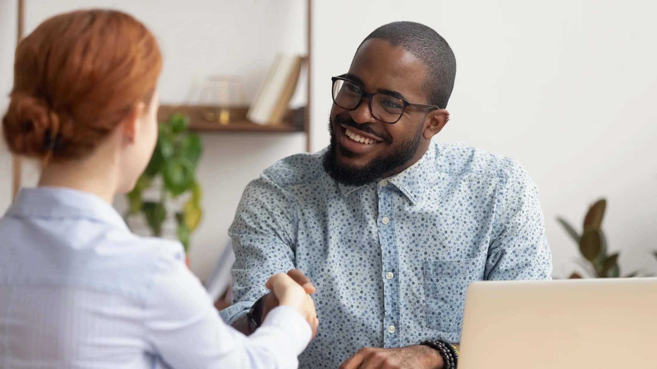 Man and woman shaking hands in office, representing fractional HR benefits.