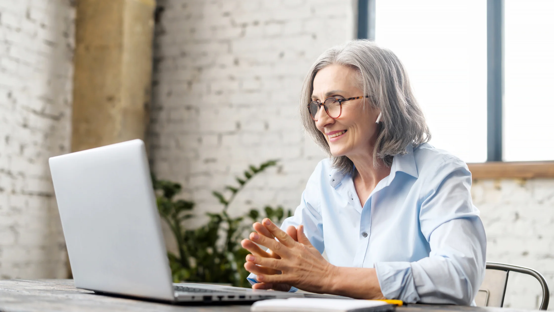 Smiling woman working on a laptop, showcasing HR outsourcing benefits for growing companies.